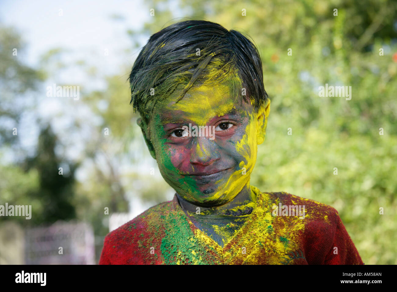 A smiling young boy shows off his colored face during festival of Holi in India. Stock Photo