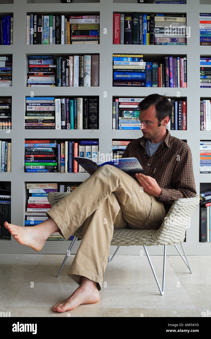South Africa, Cape Town, Camps Bay, man reading in front of a bookcase in an architects house