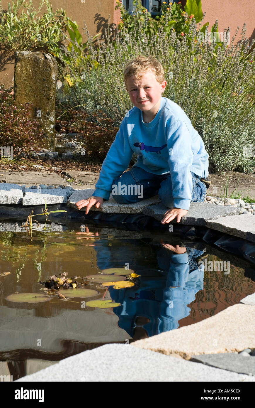 Kneeling boy, seven years old, at a pond Stock Photo