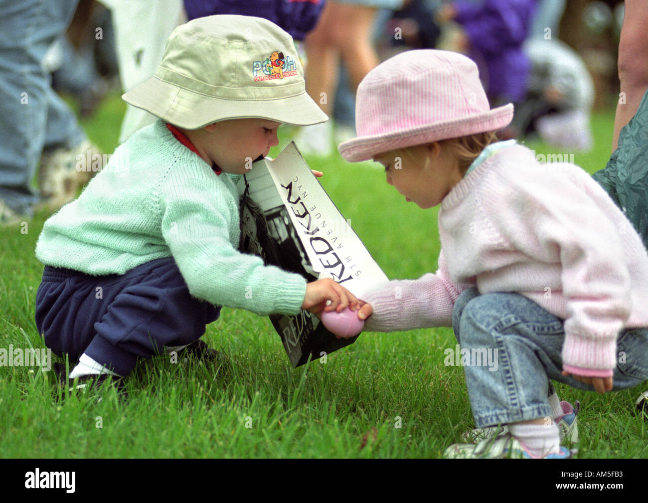Twin boy and girl grab the same plastic egg during an Easter egg hunt Stock Photo