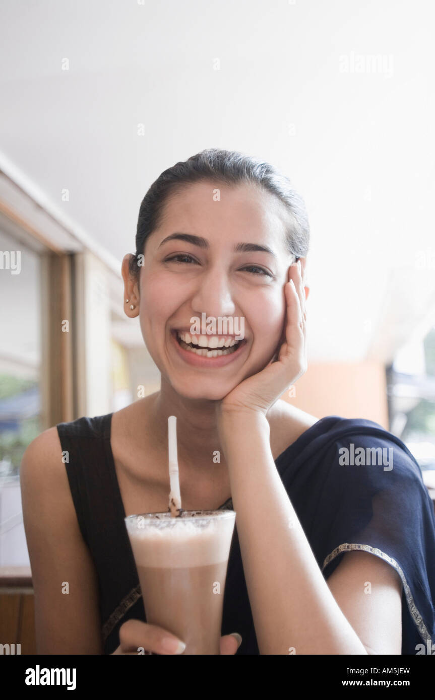 Portrait of a young woman holding a glass of chocolate milkshake and smiling Stock Photo