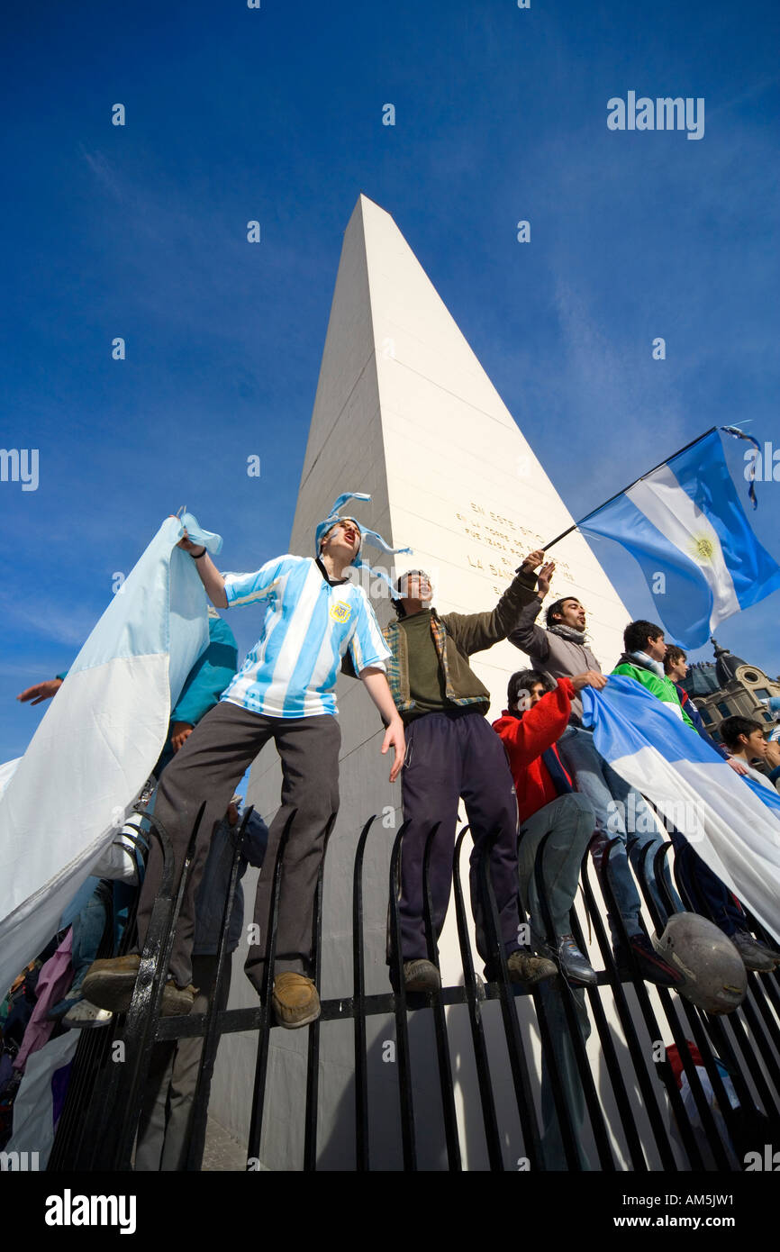 Footbal fans cheer balancing dangerously on a sharp fence around the Obelisk in Buenos Aires. Stock Photo