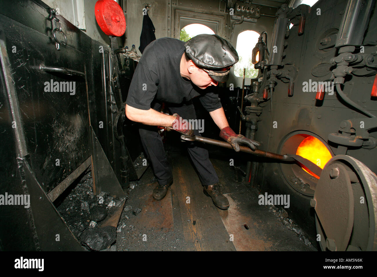 Engine driver fuelling the tank of an historical steam train Stock Photo