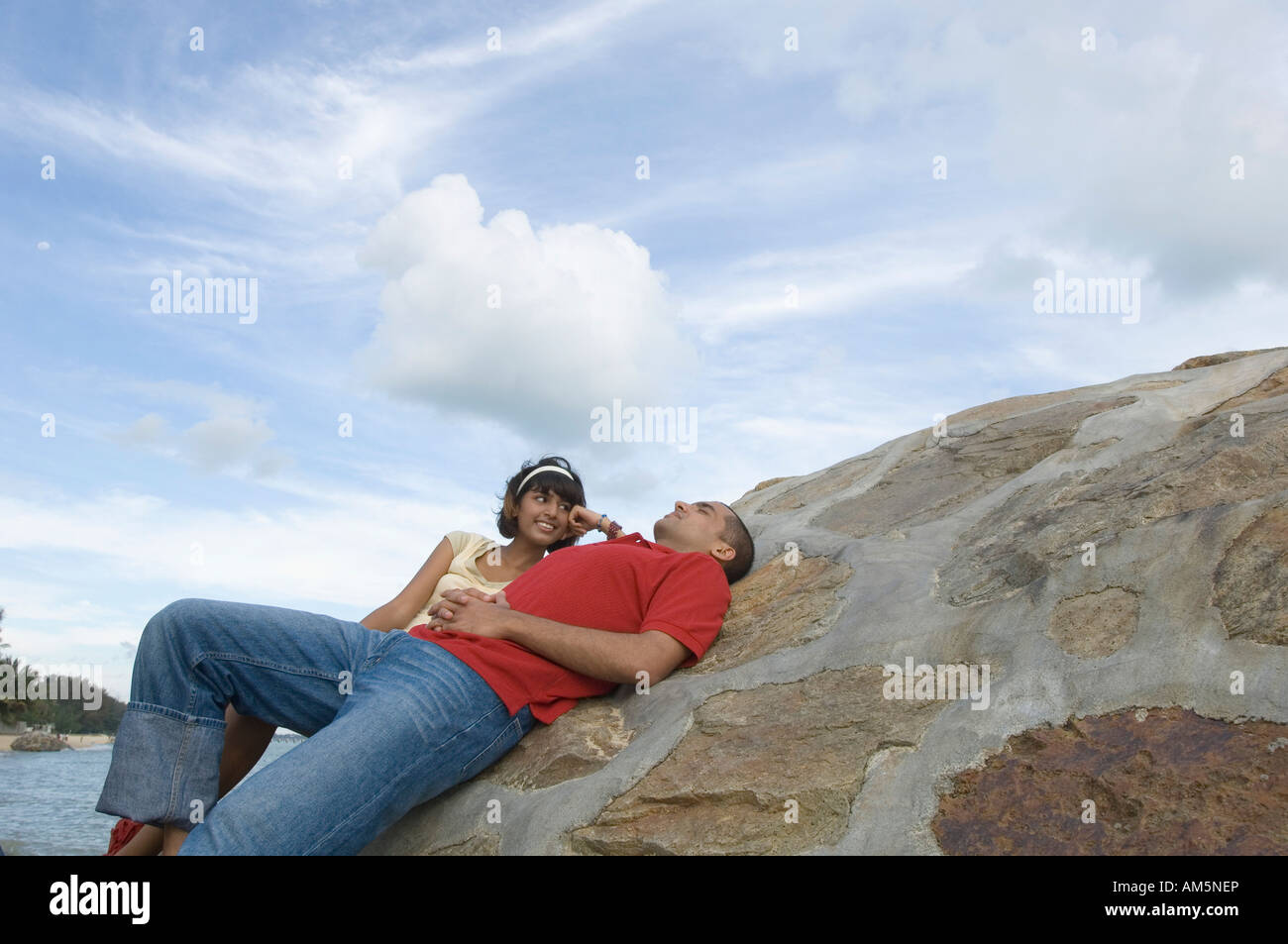 Young woman lying on the beach with a young man and smiling Stock Photo ...