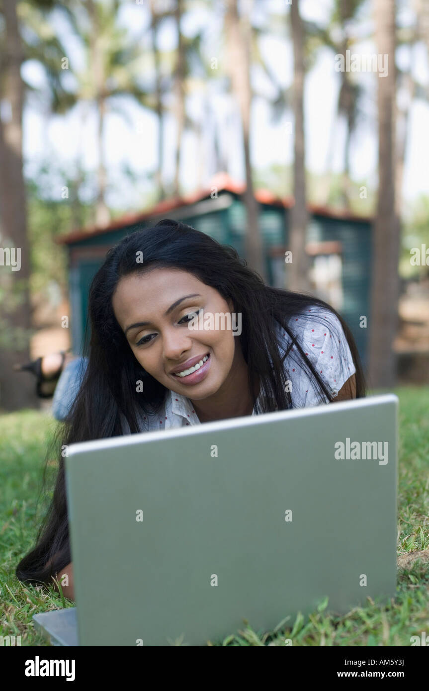 Young woman lying in a lawn and using a laptop Stock Photo - Alamy