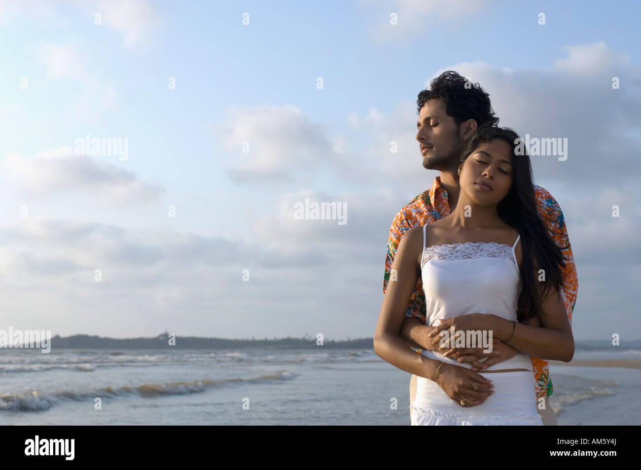 Young man embracing a young woman from behind on the beach Stock Photo ...