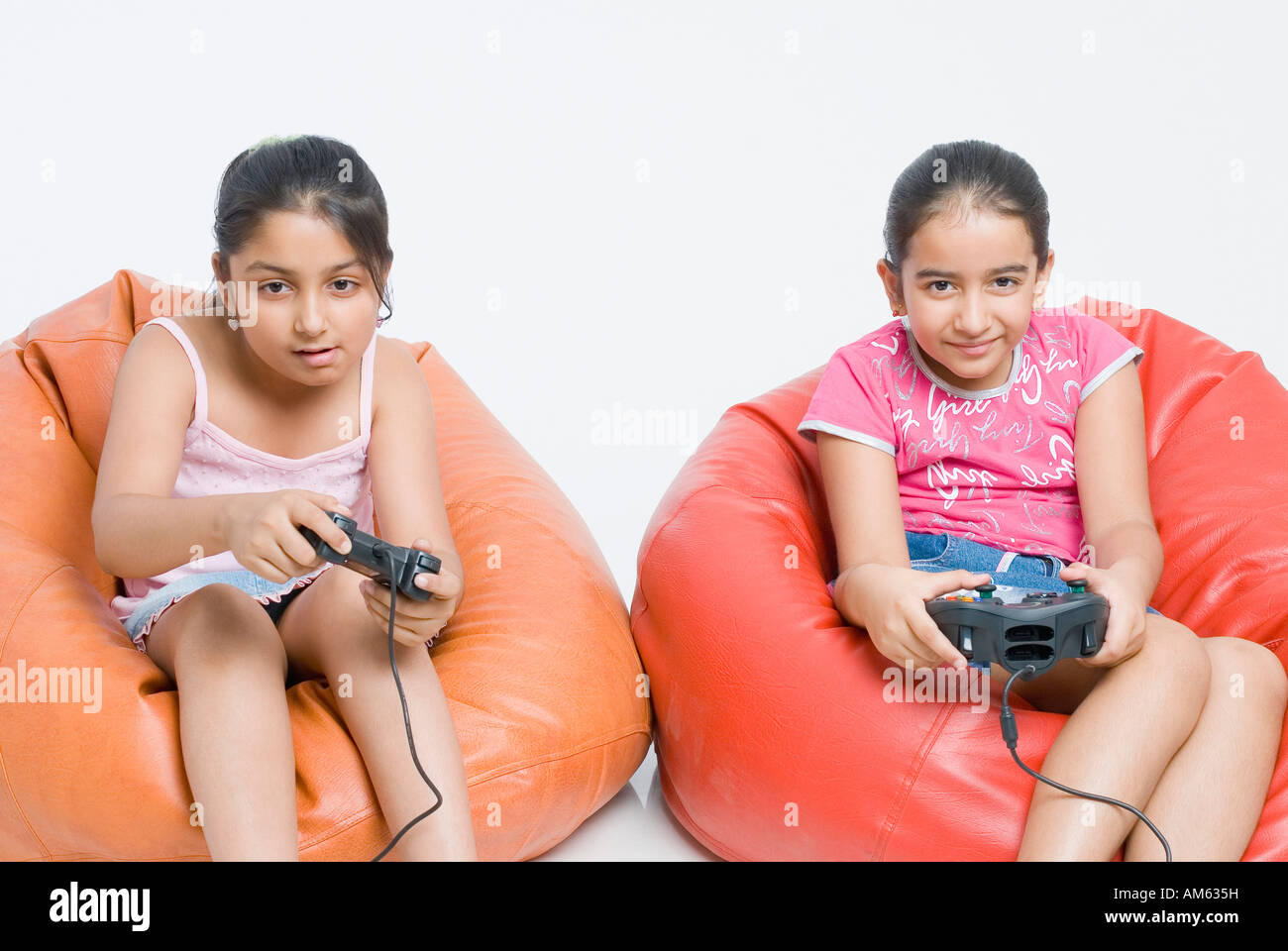 Two girls sitting on bean bags and playing a video game Stock Photo - Alamy