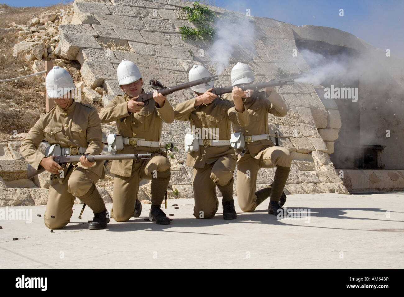 Actors dressed as soldiers in British colonial era uniforms fire a volley during a historical re-enactment at Fort Rinella, Malta Stock Photo
