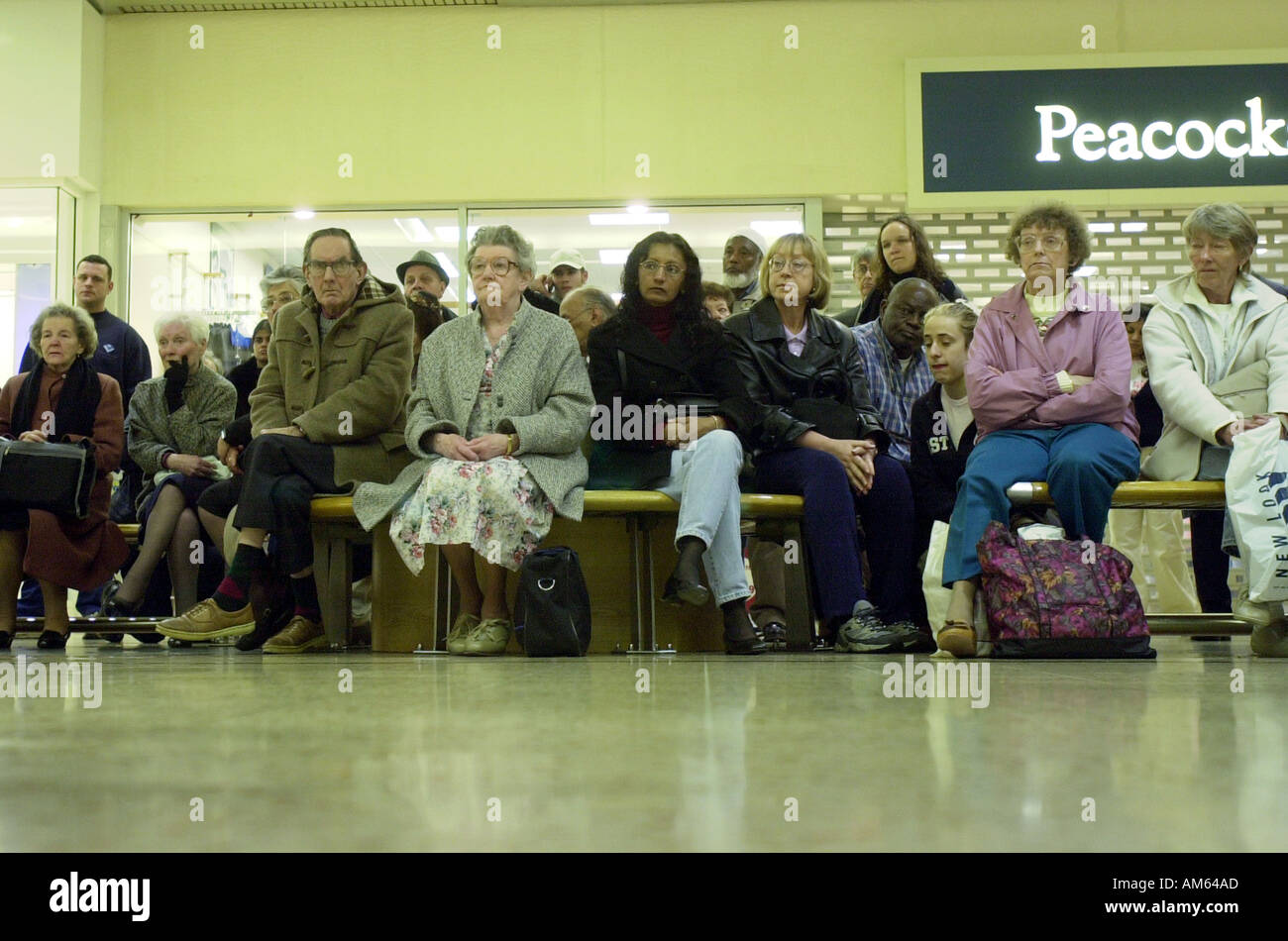 Shoppers sit and watch the funeral of the Queen mother in the Arndale centre Luton UK Stock Photo
