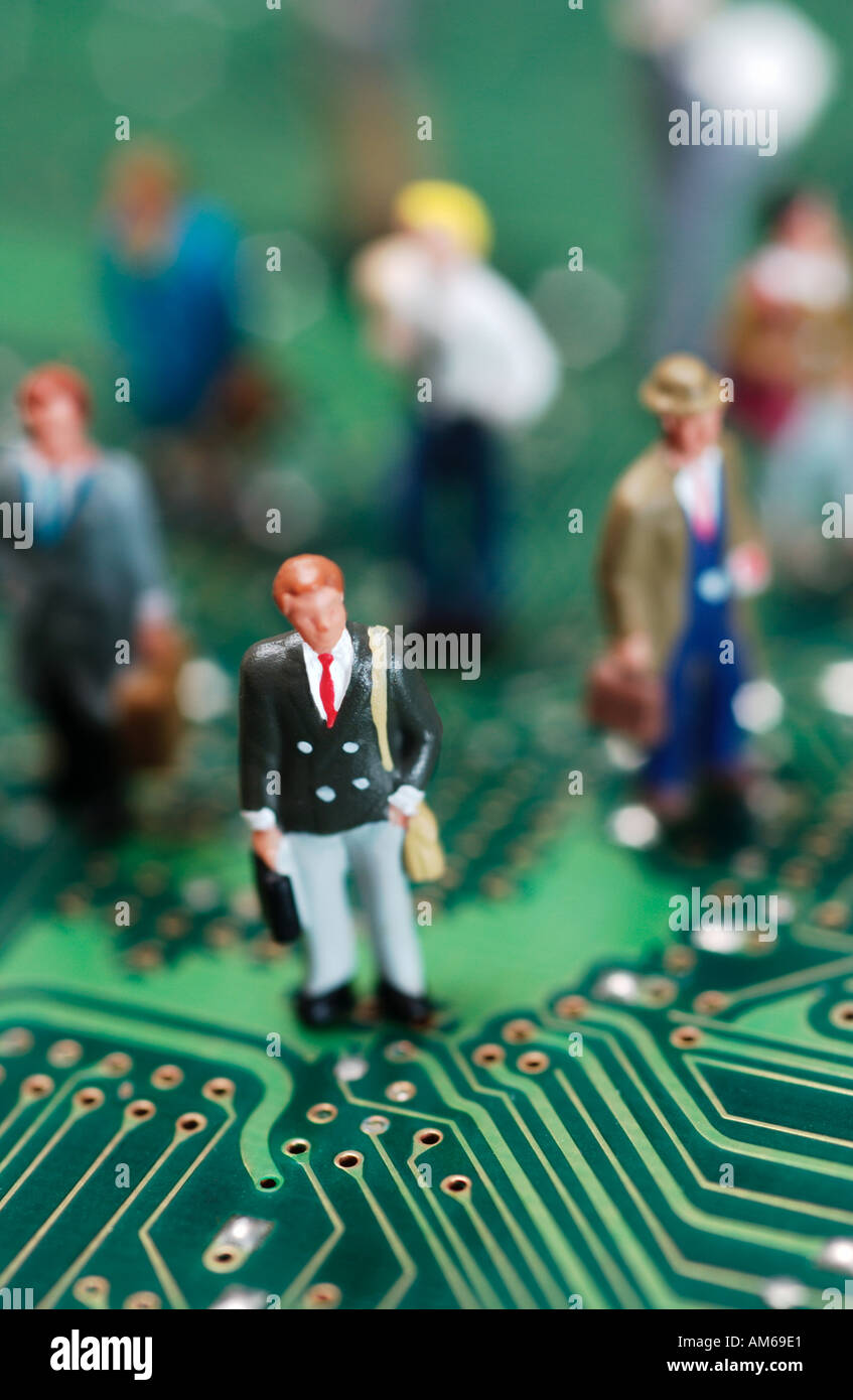 Crowd of businessmen figures standing on computer circuit board selectively focused on one businessman in foreground Stock Photo
