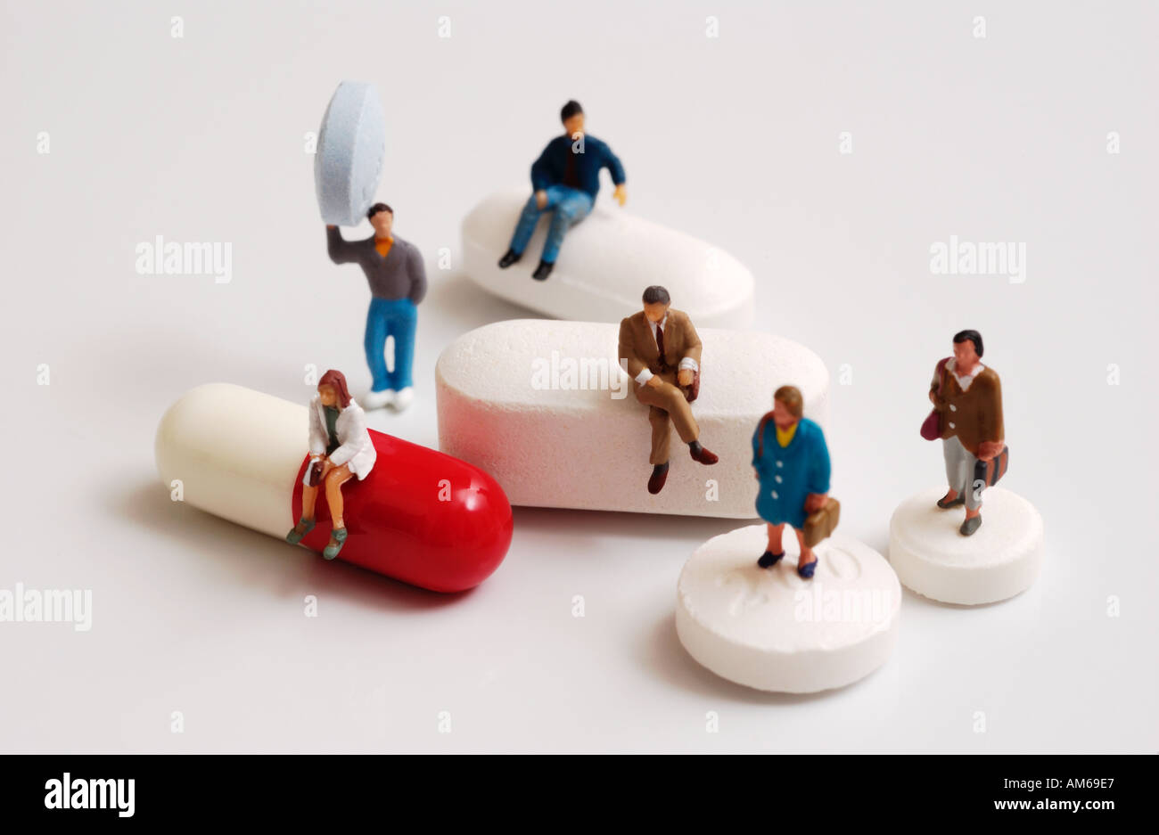 Group of tiny figures standing on sitting on and holding a variety of pills and capsules Stock Photo