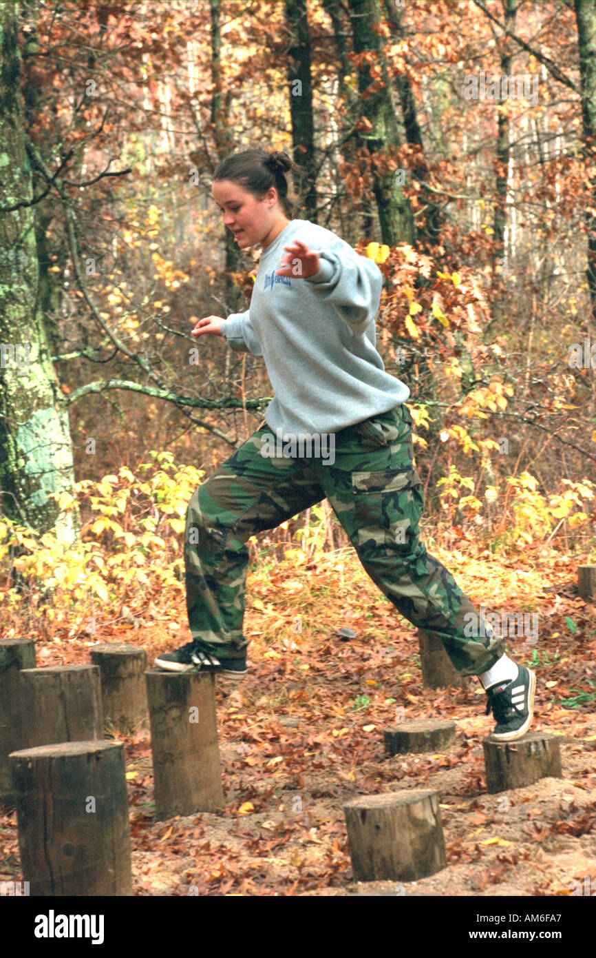 Girl 15 jumping stumps in obstacle course at youth center retreat. Camp Ripley Minnesota USA Stock Photo