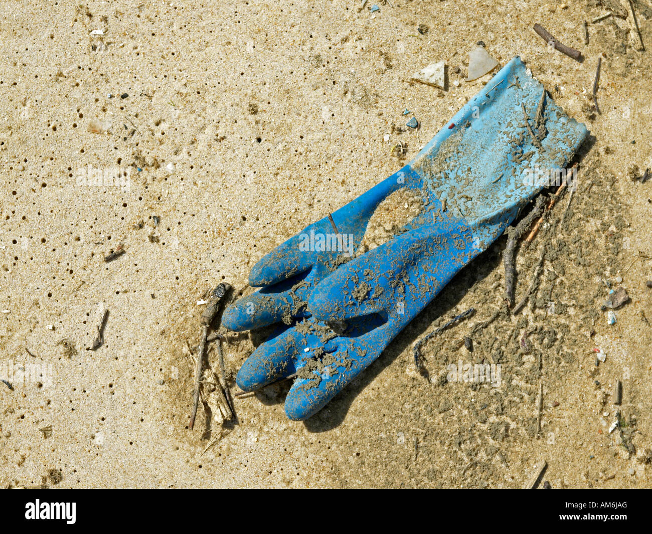old rubber working glove lying on ground on sand Stock Photo