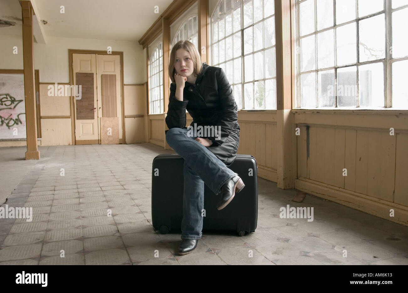 Girl Sitting On A Suit Case In A Waiting Room Of An Old