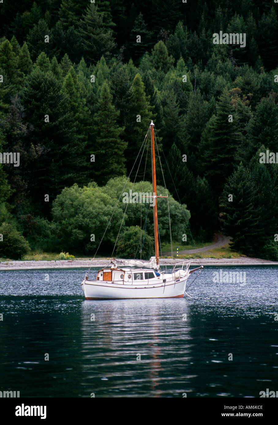 Yacht on a calm mountain lake with forest in background Stock Photo