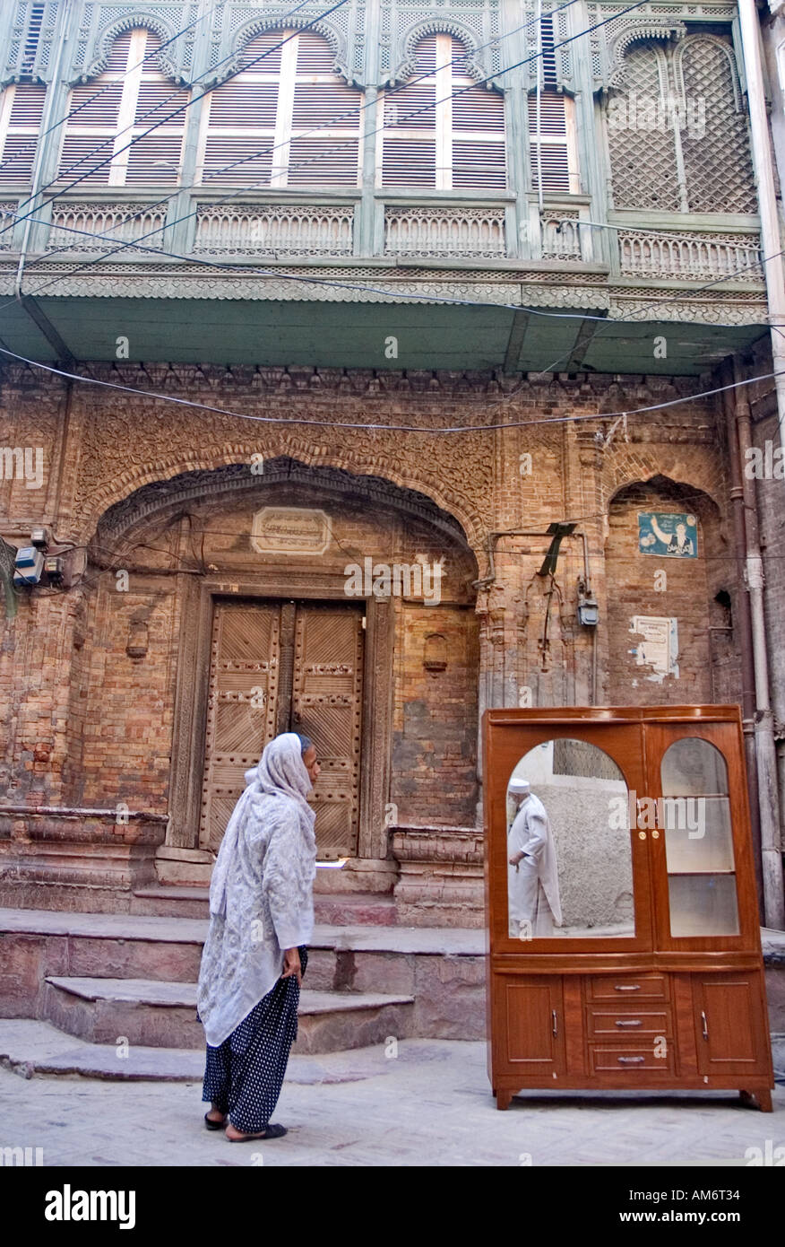 An old man is reflected into the mirror of a furniture, near an ancient