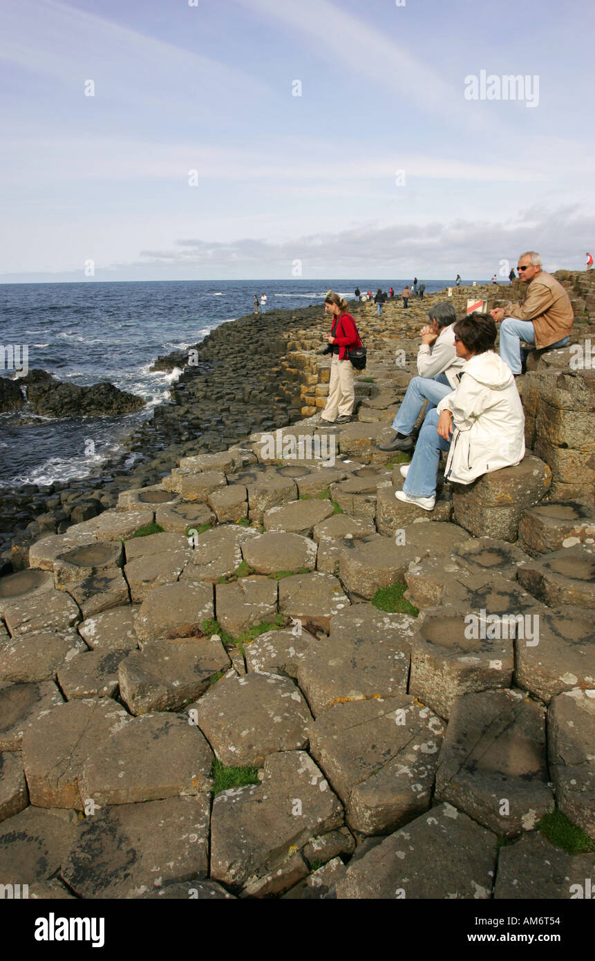 Tourists rest and admire the spectacular scenic view at the Giants Causeway, Northern Irelands famous tourism attraction NI UK Stock Photo