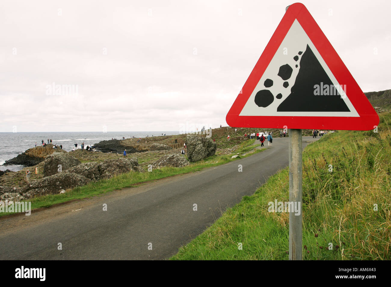 Rock fall warning sign ironically placed near cliffs and huge rocks of the Giants Causeway, Northern Ireland UK GB NI Stock Photo