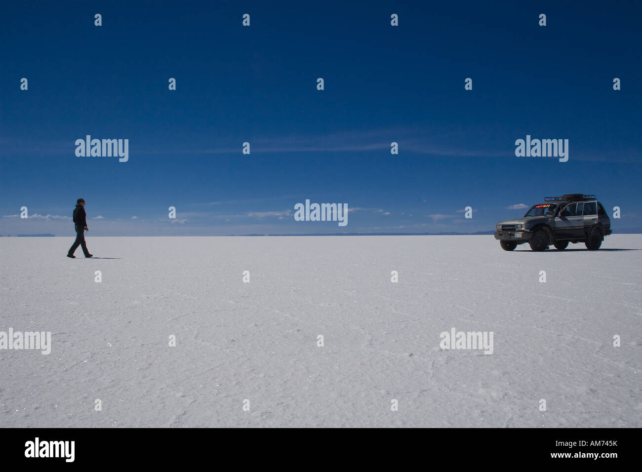 Tourist and cross-country vehicle on Salar de Uyuni, Uyuni, Bolivia Stock Photo