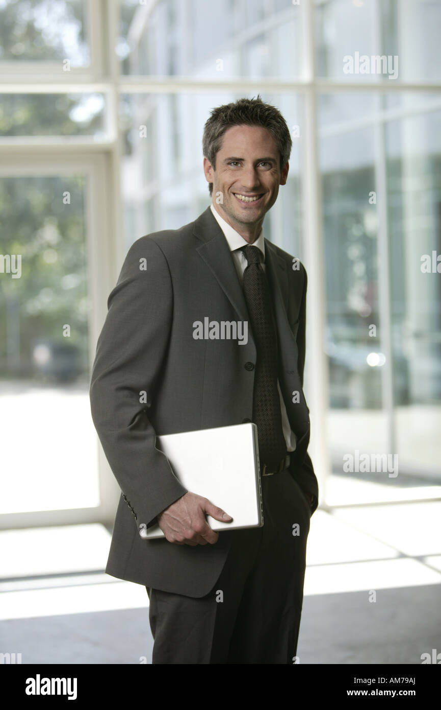 Business man with laptop in the lobby smiling Stock Photo