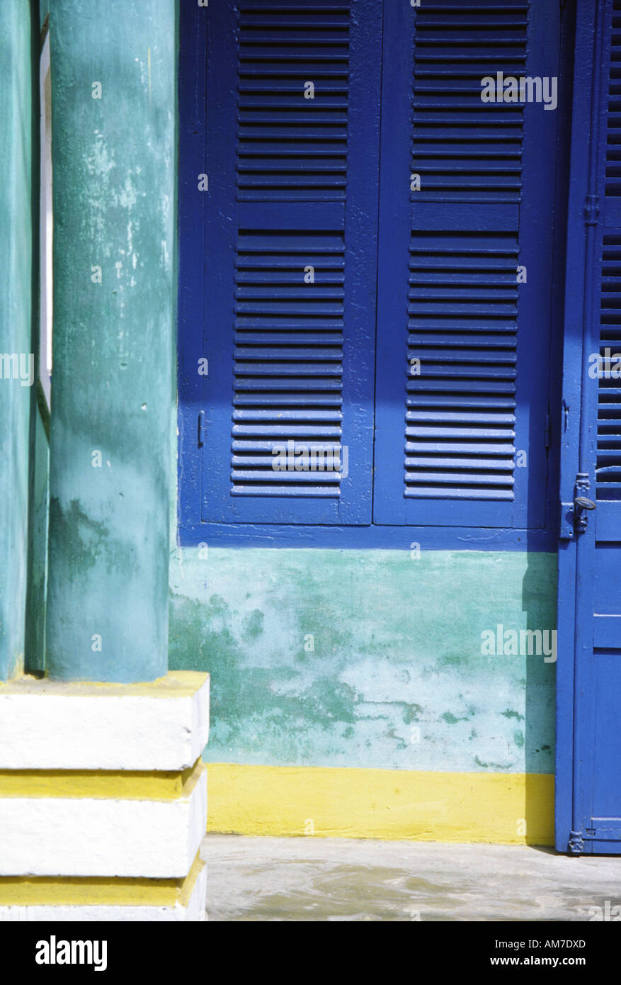 Detail of blue shutter and green stained wall and pillar in a covered walkway in Hoi An Vietnam Stock Photo