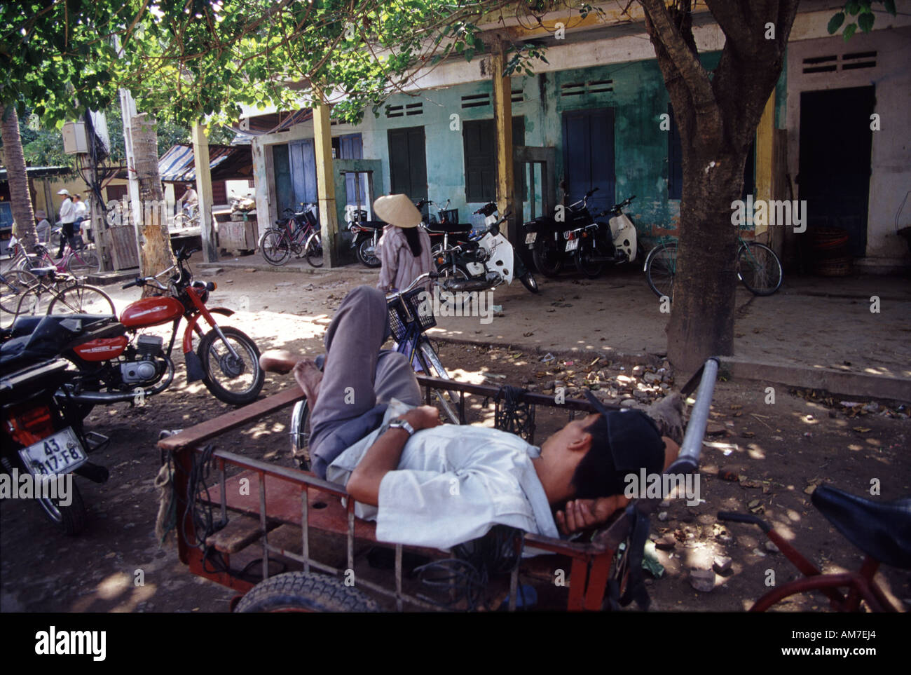 Man sleeping on bike trolley under a shady tree in Hoi An Vietnam Stock Photo