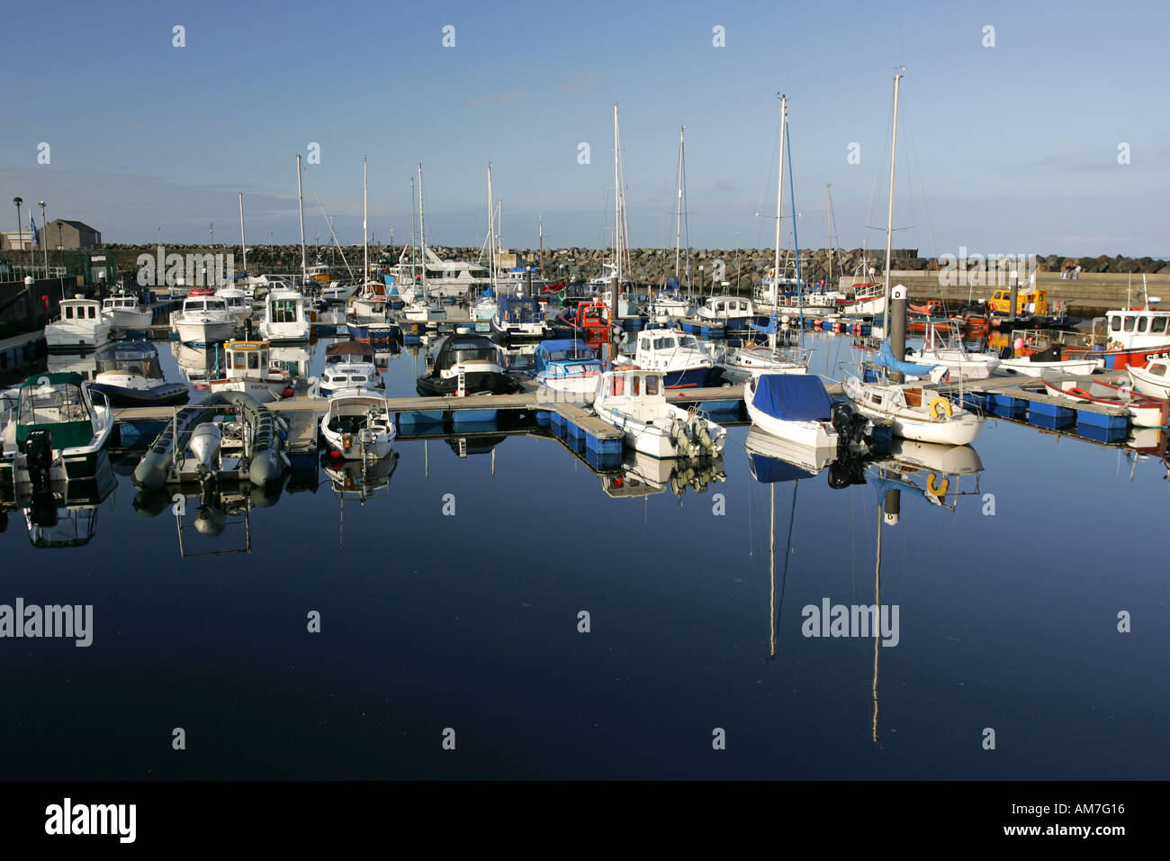 Boats moored in Ballycastle Harbour reflect in the still inner harbour water, County Antrim North coast Northern Ireland NI GB Stock Photo