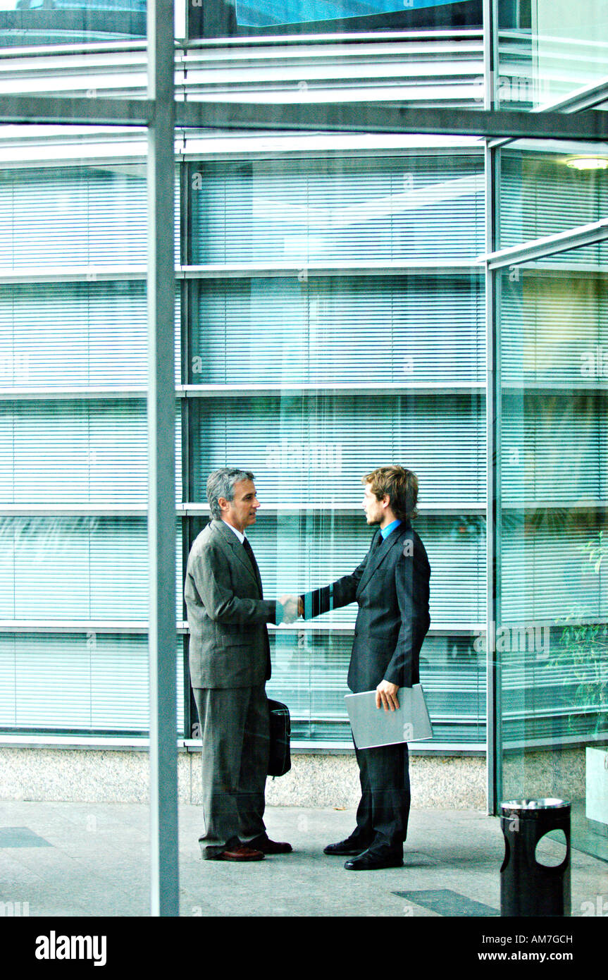 Businessmen shaking hands by office building Stock Photo - Alamy