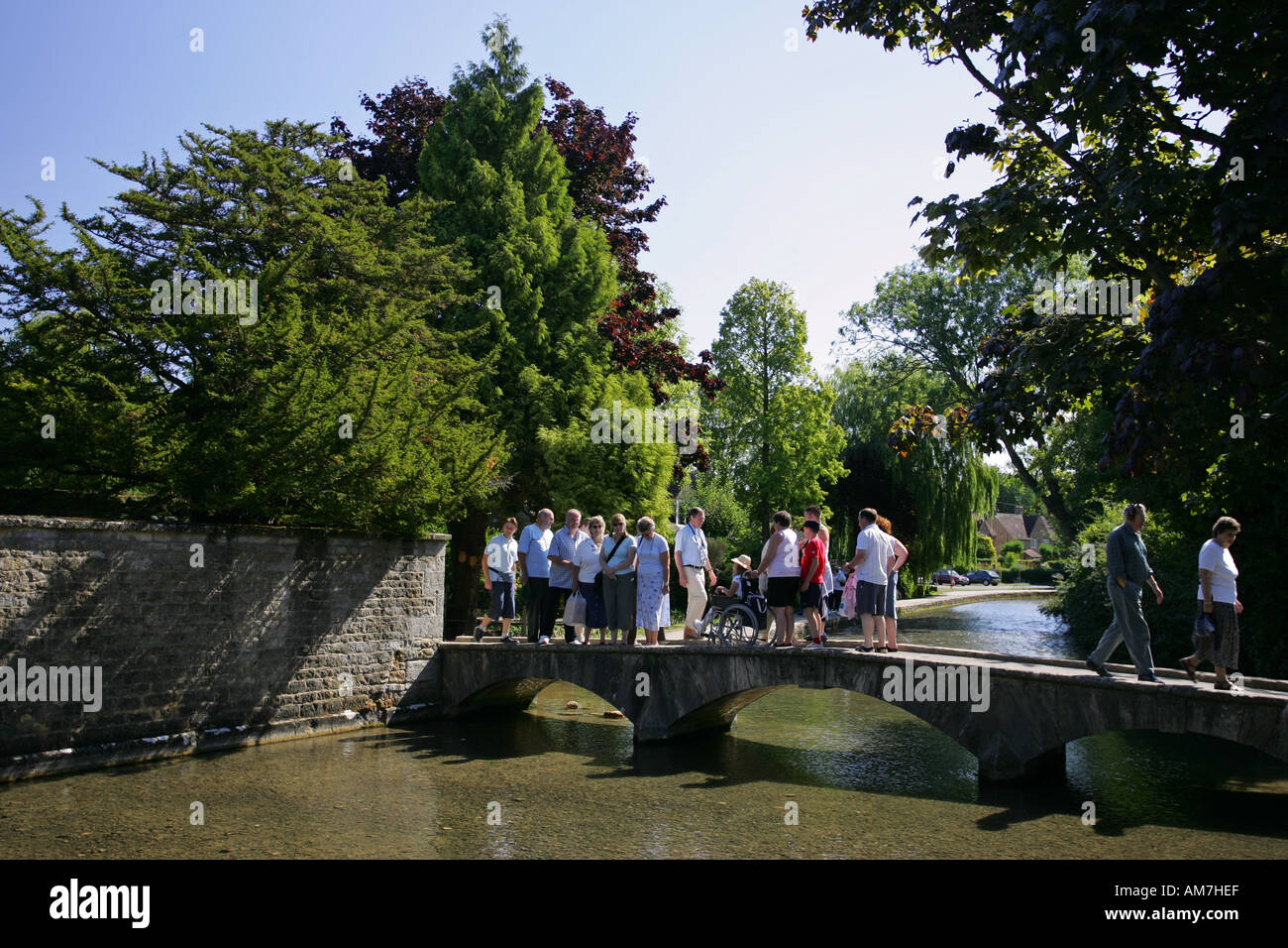 Group of tourists stand on a bridge posing for a photograph Bourton On The Water the Cotswolds Gloucestershire England UK GB Stock Photo