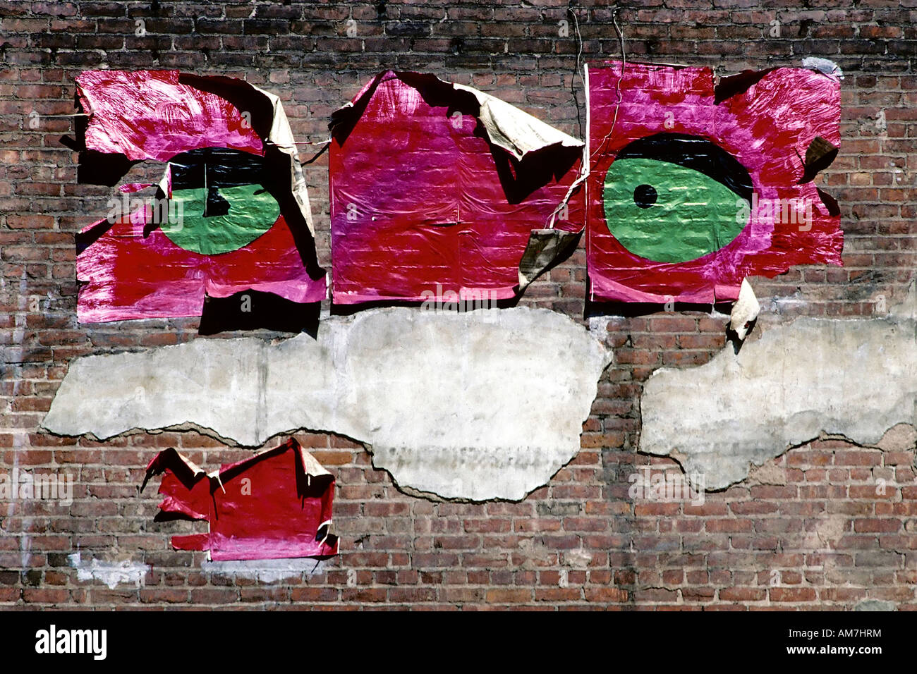 Rip of poster with big green eyes on a brick wall, New York City, USA Stock Photo