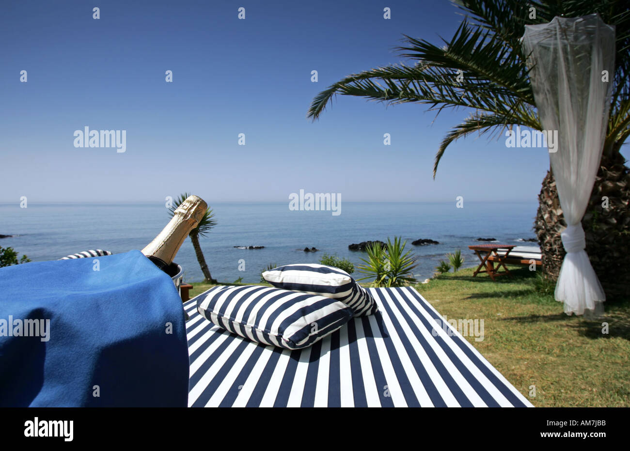 Champagne and bucket next to sunlounger overlooking Mediterranean Sea Stock Photo