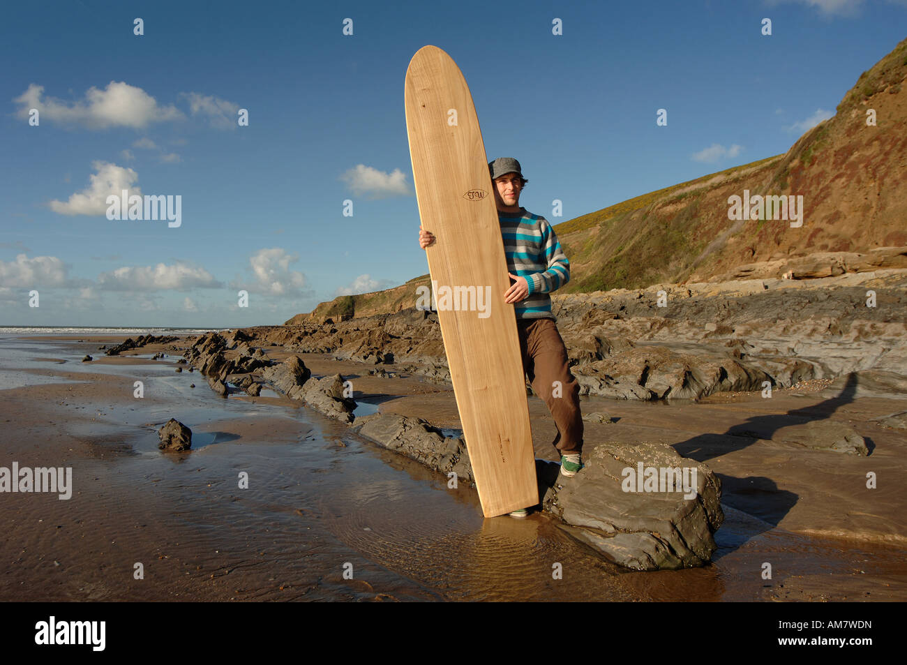 a surfer holding a tom wegener surfboard on the beach at Saunton Sands beach in North Devon UK. Stock Photo