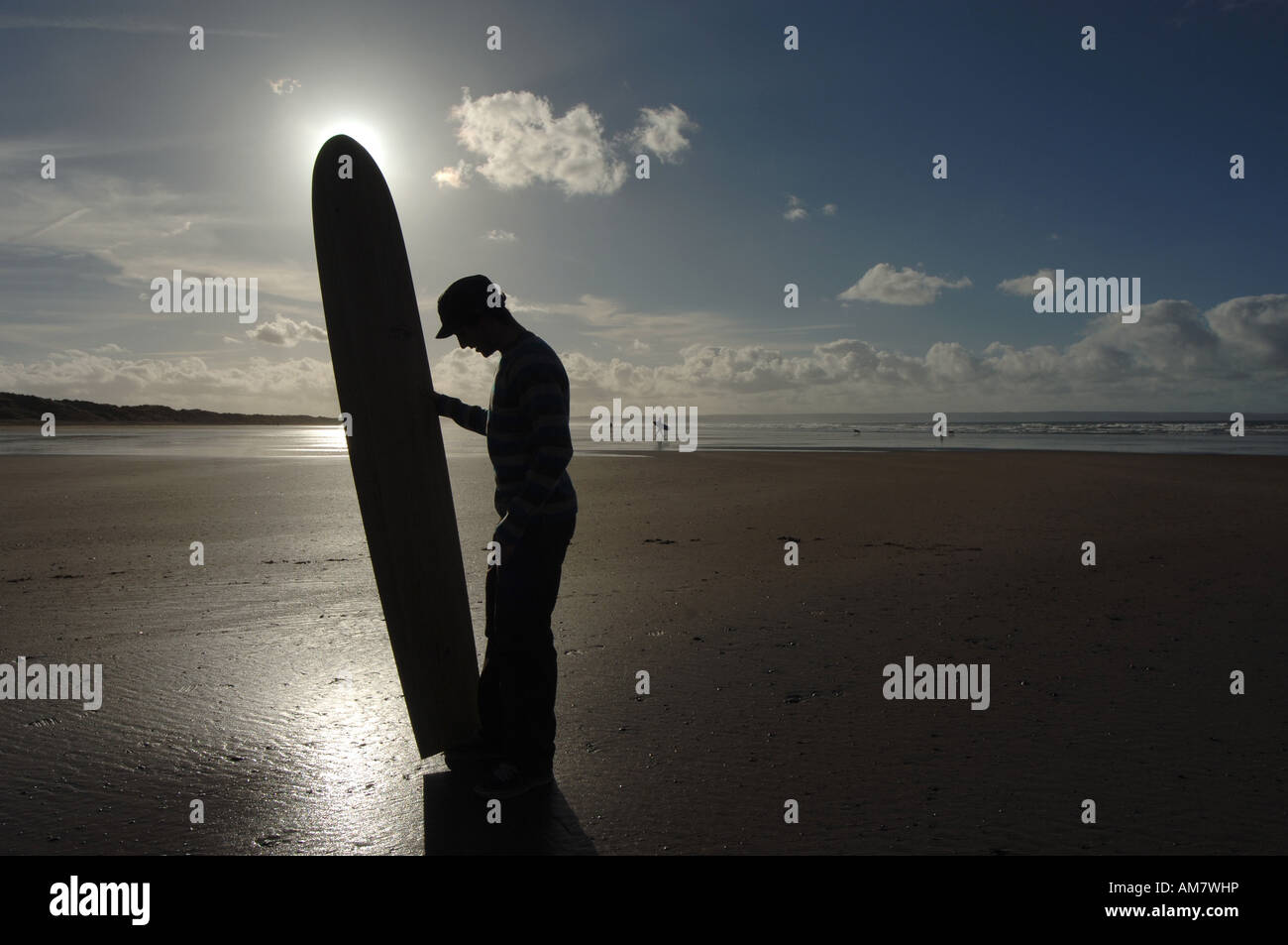 a surfer holding a tom wegener surfboard on the beach at Saunton Sands beach in North Devon UK. Stock Photo