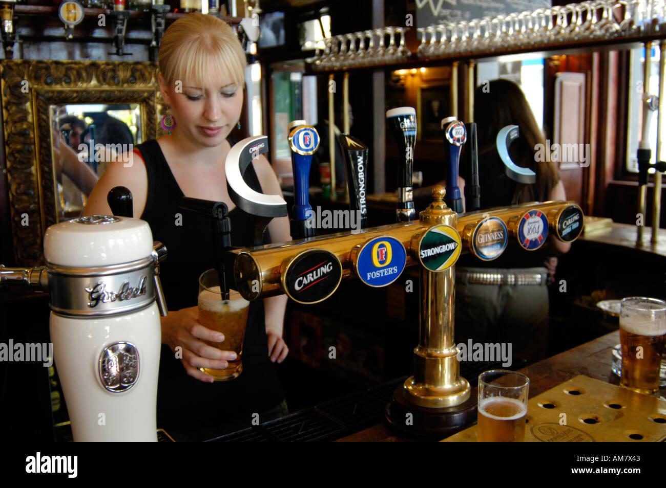 Pub barmaid pouring pint of lager in pub, Camden Town, London England UK Stock Photo