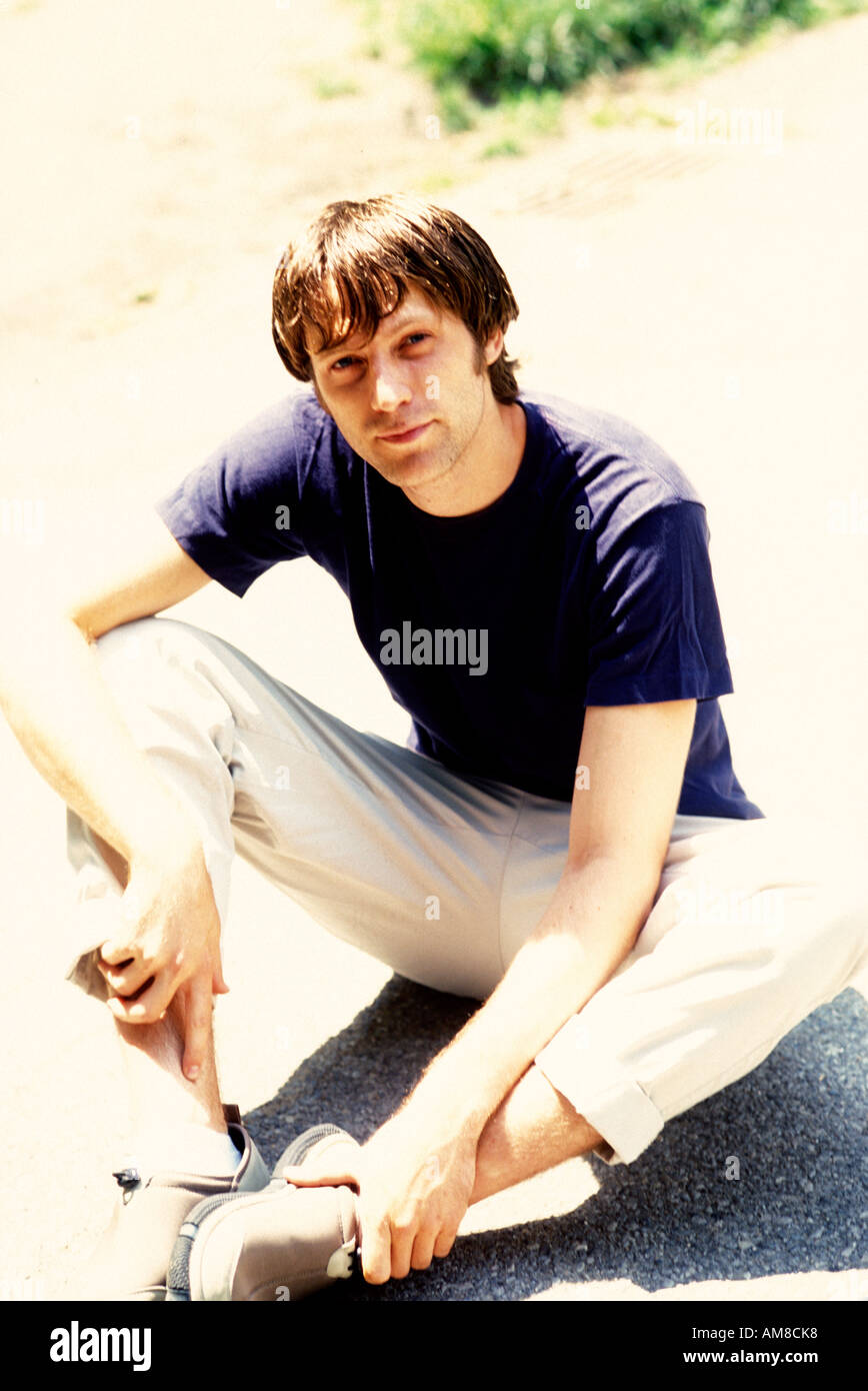 Young man sitting on road, portrait Stock Photo
