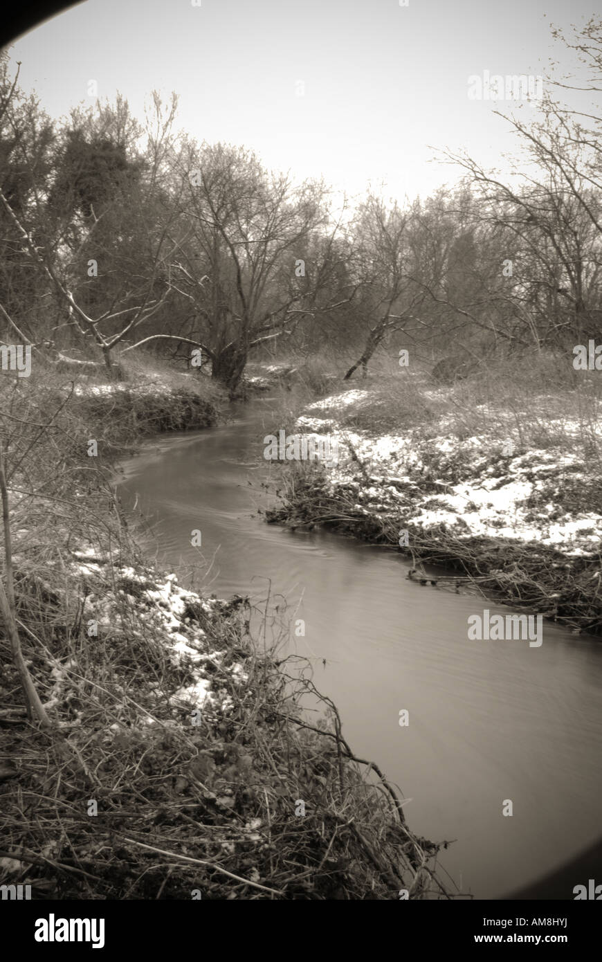 A small flowing river stream on a snowing winters day Stock Photo