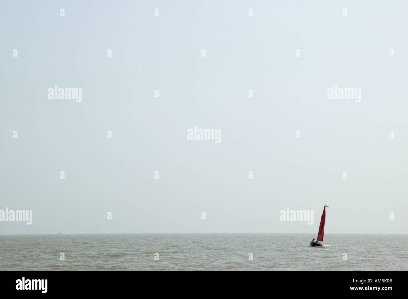 single red sailing boat in large expanse of water. Concepts of