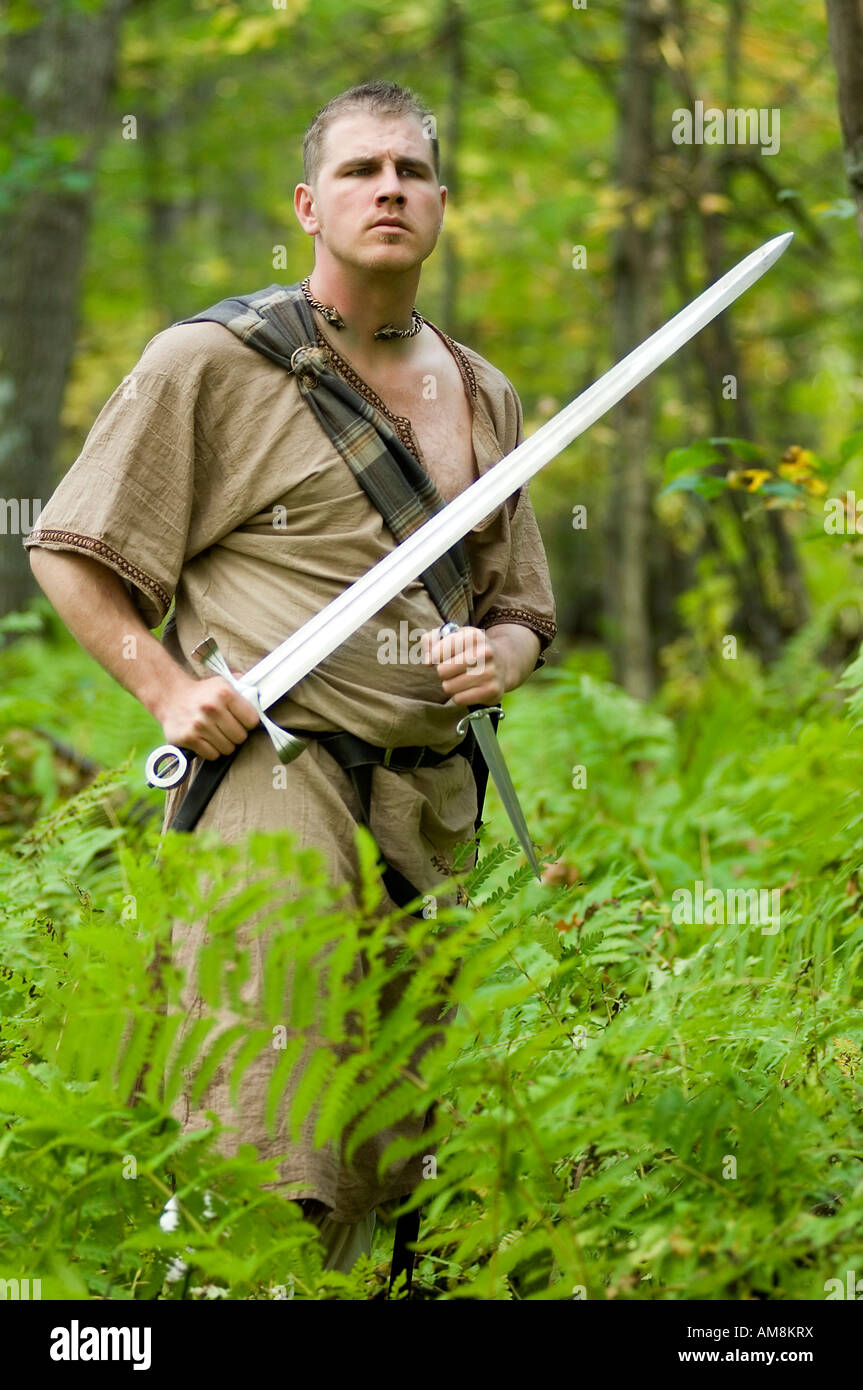A Celtic warrior standing in ferns with a sword and dagger Stock Photo