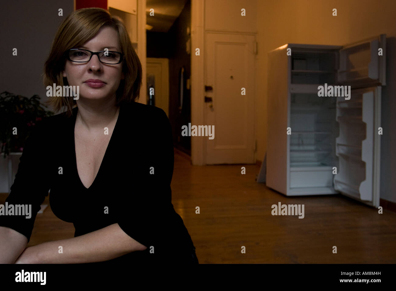 woman with red hair in an empty new york apartment, wearing black rimmed glasses Stock Photo