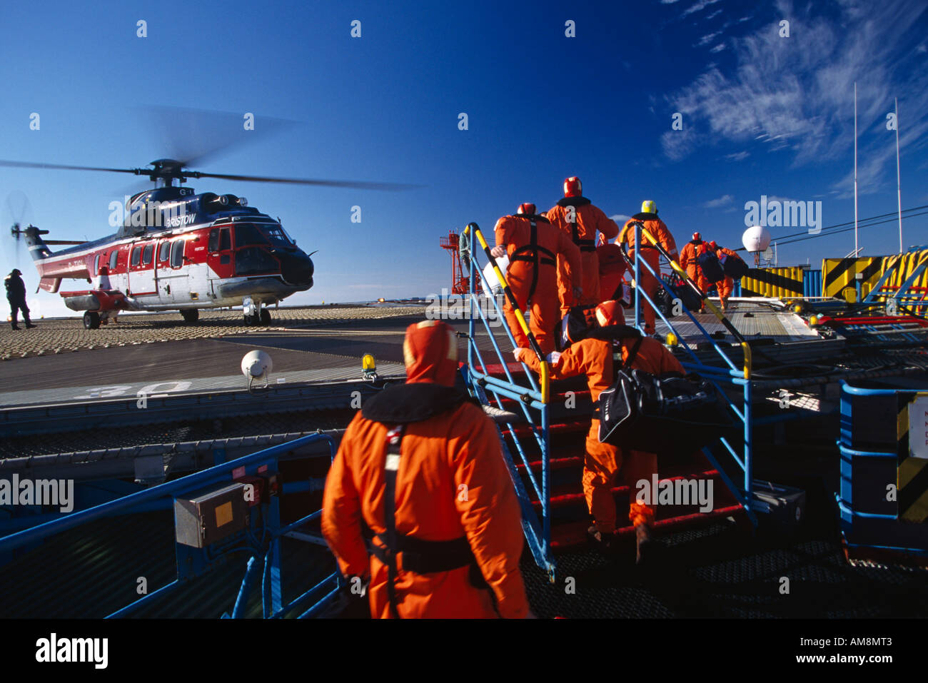Offshore Oil Platform personnel crew change boarding helicopter on oil rig in the North Sea with Puma helicopter in background Stock Photo