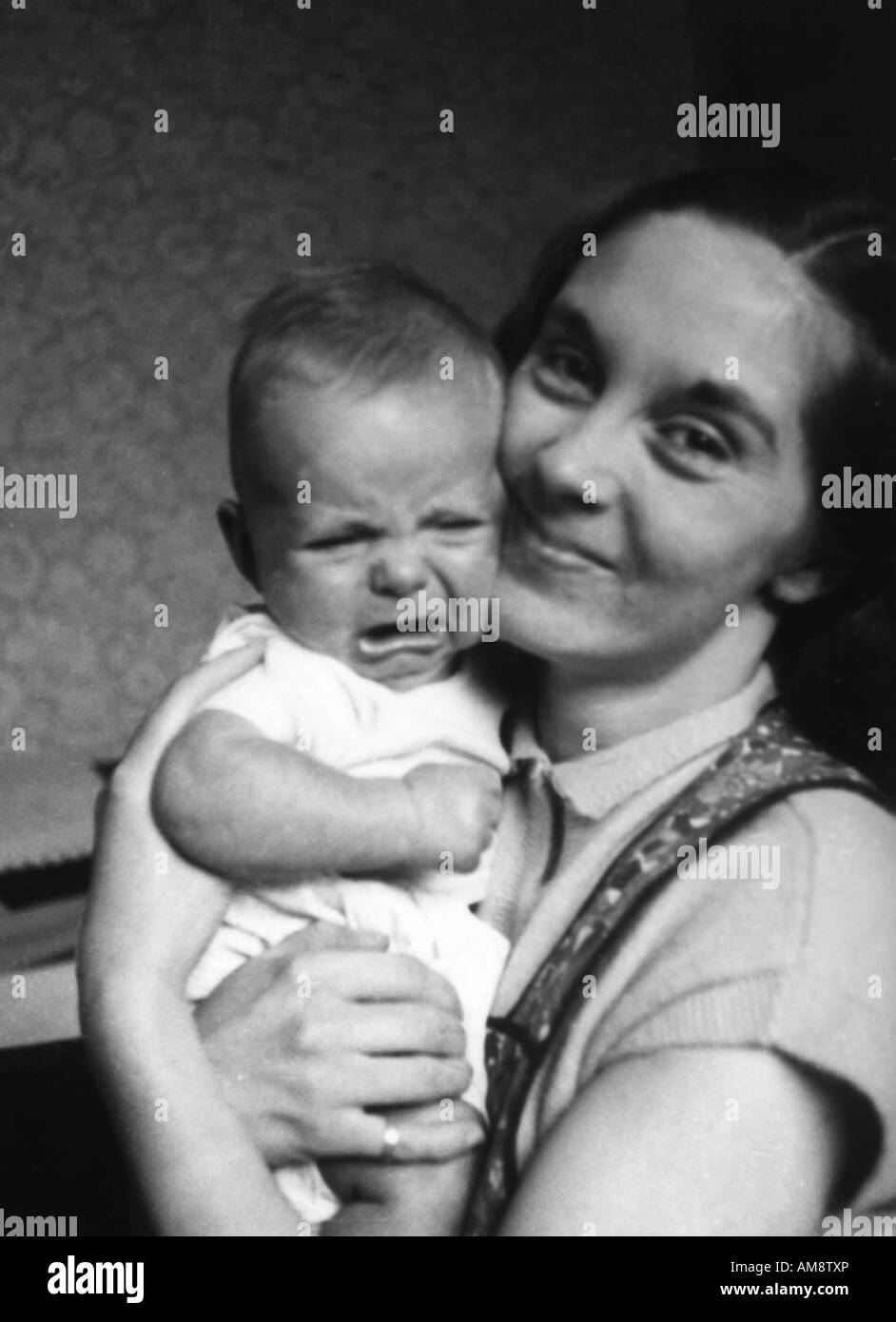 OLD VINTAGE BLACK AND WHITE FAMILY SNAPSHOT PHOTOGRAPH OF YOUNG MOTHER CUDDLING CRYING BABY BOY Stock Photo