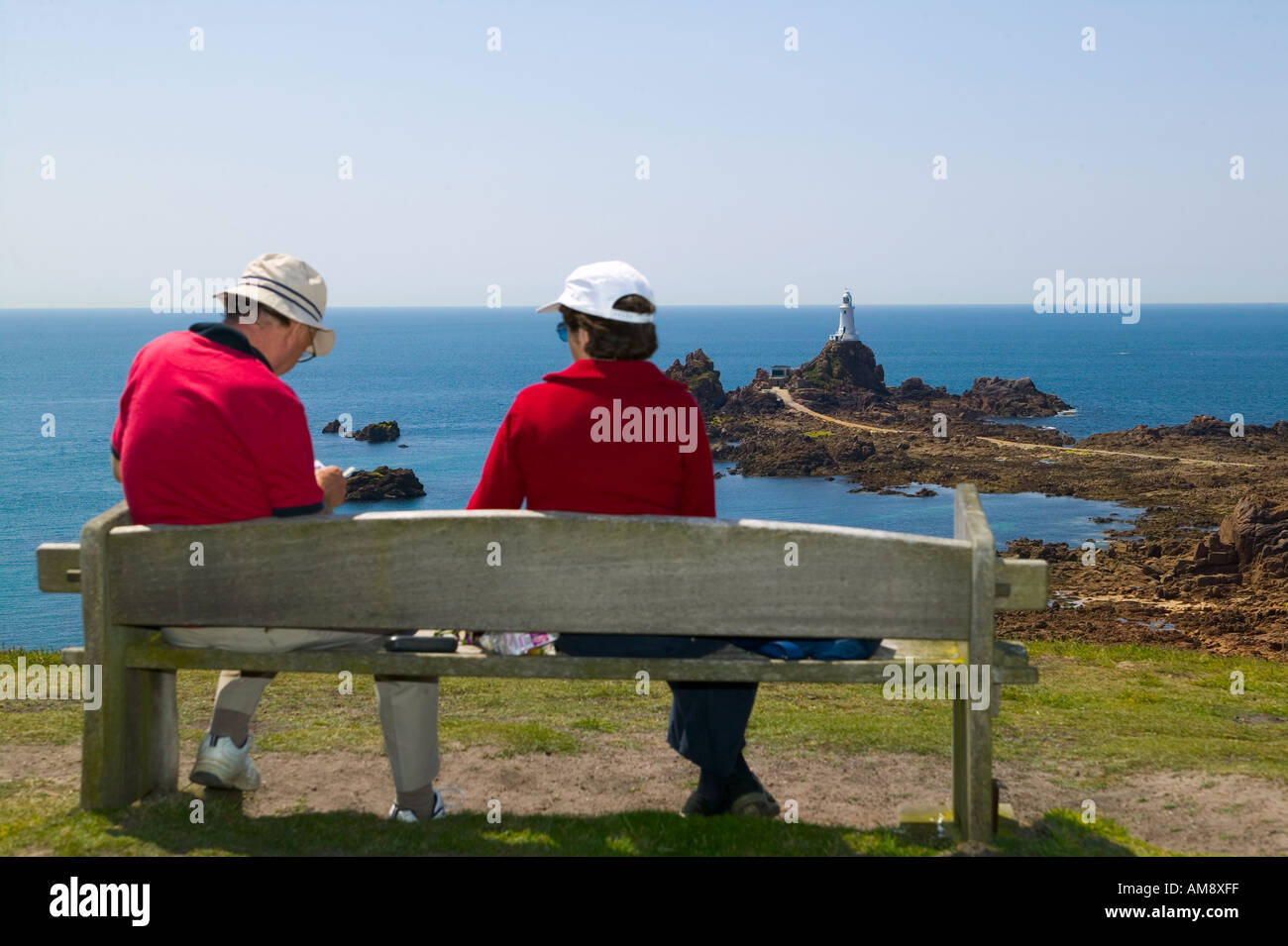 Tourists wearing red t-shorts and wearing hats at Corbiere Lighthouse on the island of Jersey Stock Photo