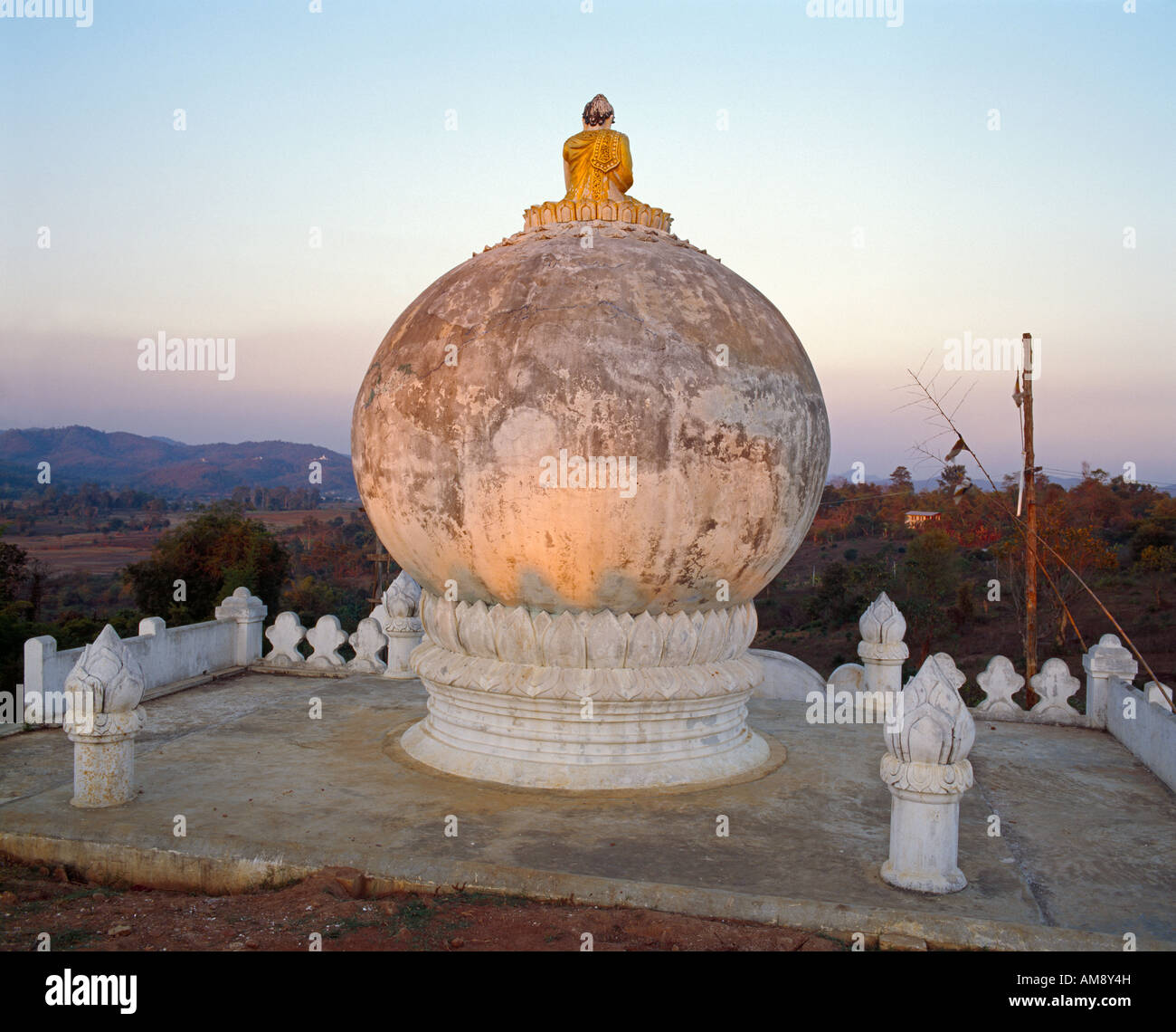Buddhafigur sitzt auf  Weltenkugel und schaut in die Landschaft buddha staue sitting on a globe looking out in the landscape Stock Photo
