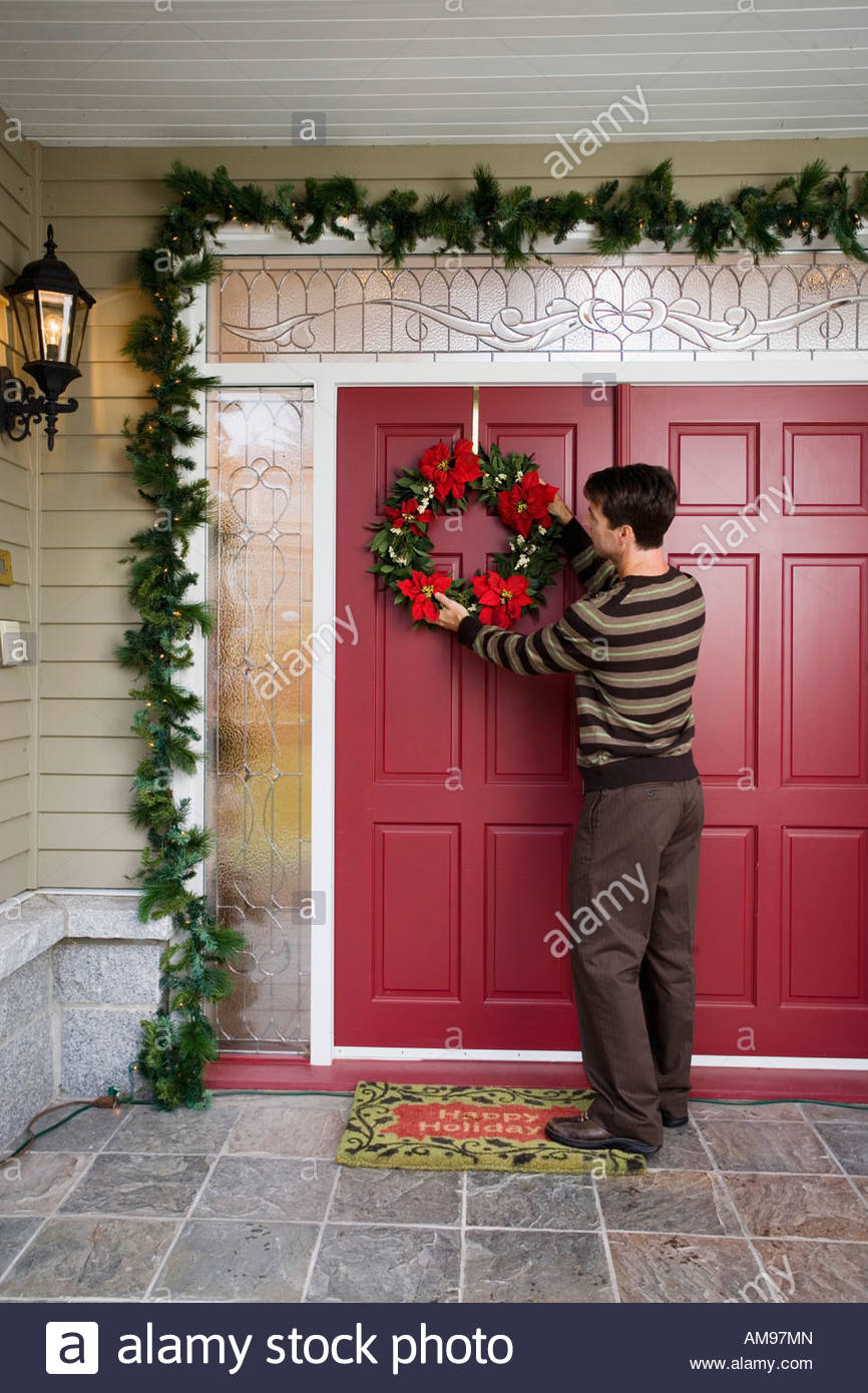 Man Hanging Christmas Wreath On Front Door Stock Photo