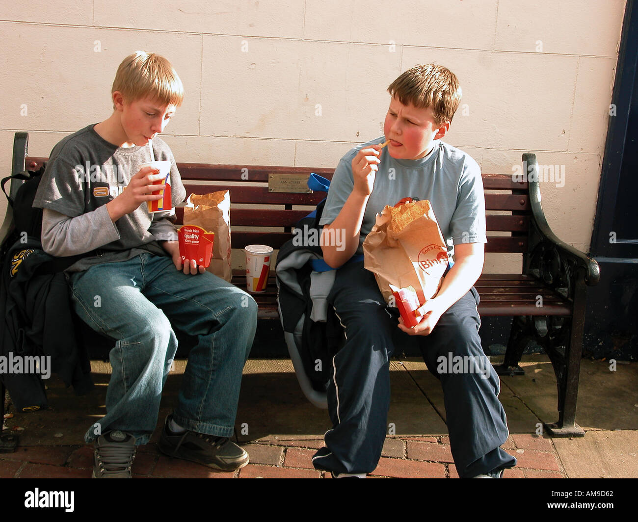 Two Boys Sitting On Bench Eating Fast Food Stock Photo 1351009