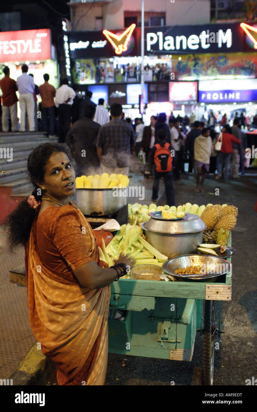 A woman with a handcart sells corn and pineapple on the corner of Church Street and Brigade Road, Bangalore, India Stock Photo