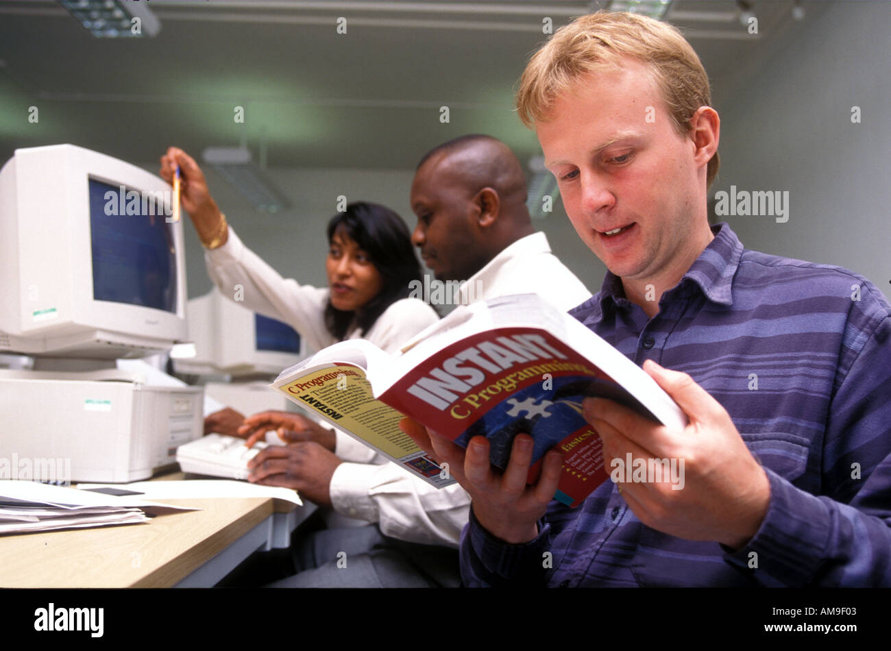 Multiracial group of further education students studying on computers. Stock Photo