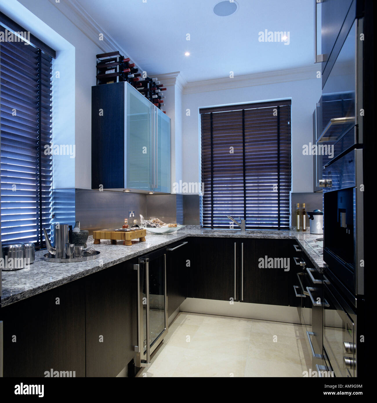 Lit kitchen with black cupboards and marble worktop in luxury London