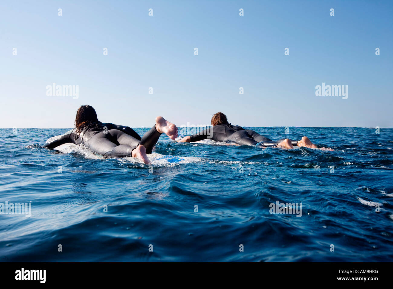 Couple going out on surfboards in the water. Stock Photo