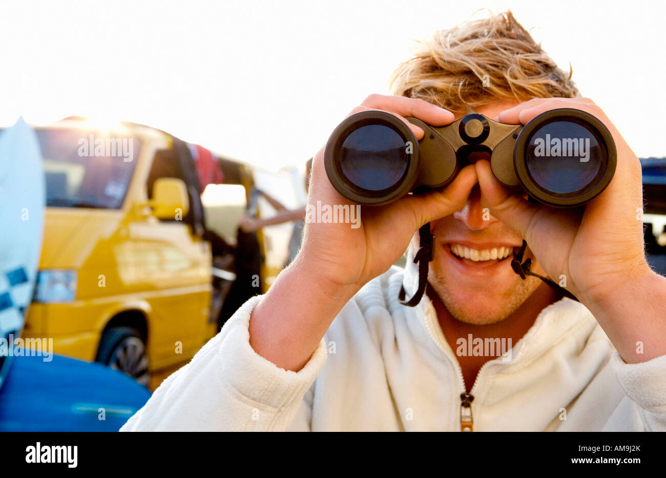 Man on beach with binoculars smiling with woman unloading van at the beach . Stock Photo